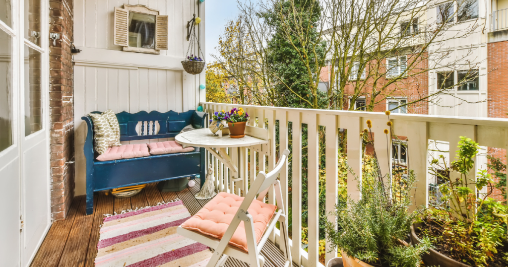 Petit balcon champêtre aménagé d'un mobilier, coussins et tapis colorés