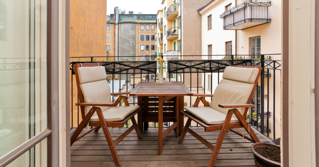 Petit balcon avec mobilier en bois orangé et agrémenté de coussins blancs